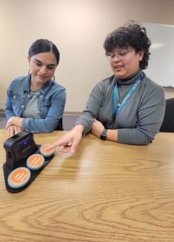 Lizette, Assistive Technology Coordinator (right), and Michelle, Director of Care Services (left), demonstrating how to use AT Speakers.
