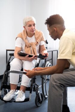 Pictured, older adult in a wheelchair being shown by younger adult how to access resources and information