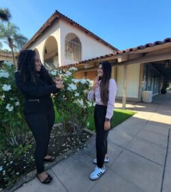 Pictured DMC’s Deaf Services Team Members Pamela (left) and Doryna (right) having a conversation outside smiling.