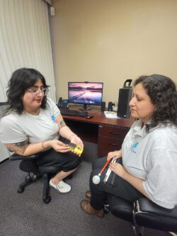 DMC’s ILS Instructors for the Blind Christabel Andrarade using recorder in demonstration to Gabriela Alvarez.