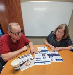 Pictured, older adults looking at DMC flyers at table.