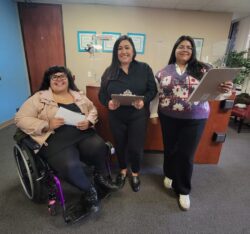 DMC’s Front Office Team smiling happy to meet and greet our community visitors. Nelly, Bianca and Paola at the front office reception area. Nelly is holding mail, Bianca is holding a clipboard and Paola is holding a calendar.
