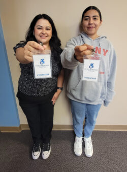 Volunteer Coordinator, Raquel with Volunteer Sam holding badges