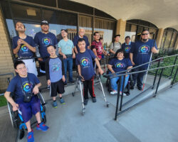 Pictured DMC Summer Youth Academy participants with Team DMC Youth Connect and DMC Board President and VP outside of DMC on ramp smiling, wearing Summer Youth Academy shirts, having fun connecting.
