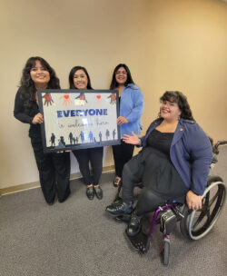 Pictured: DMC’s I&R Team – Mareli, Bianca, Paola and Nelly in hallway with a sign which reads “Everyone is welcome here