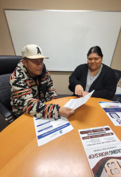 Community Living Advocate, Esme showing Consumer ILS skills to independently advocate for one’s self through information resources at table