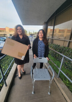 DMC Community Transitions Team L-R: Marisol Johnson (holding moving box) and Lizeth Arroyo (with DME chair) on ramp outside DMC.