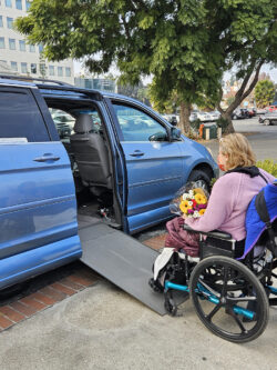 DMC Consumer Martha entering van with flowers via vehicle ramp lift to go home.
