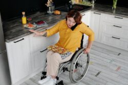 Person with disabilities in kitchen multitasking daily living skills preparing a meal in the kitchen while talking on the phone using communication social skills navigating use of a wheelchair at the same time safely.