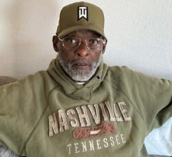 DMC Veteran Consumer Caleb T. in olive green sweatshirt and cap with glasses and grey beard