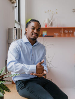 Businessman with hearing aid using sign language SIGNING "help" in ASL in a modern office space, promoting individuality and communication.